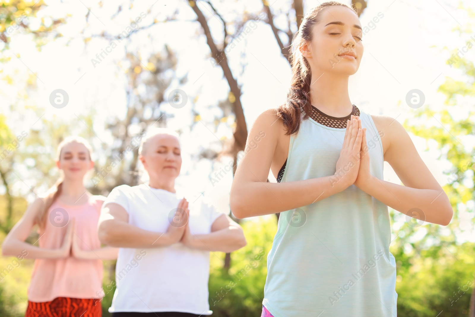 Photo of Group of women practicing yoga in park on sunny day