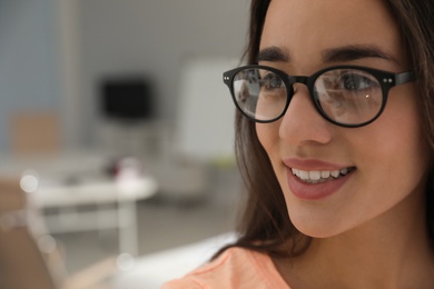 Beautiful young woman wearing glasses on blurred background, space for text. Ophthalmologist service