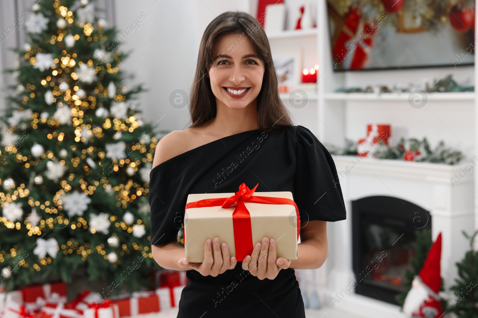 Photo of Smiling woman with Christmas gift at home