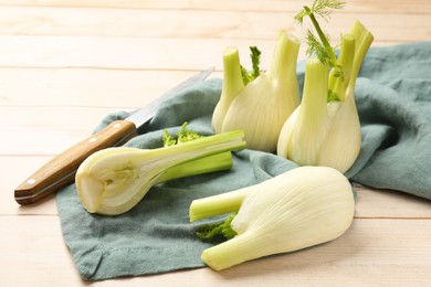 Photo of Fresh raw fennel bulbs and knife on light wooden table