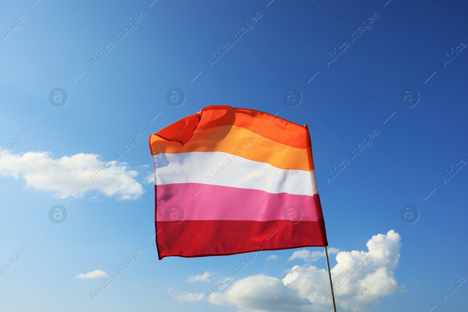 Photo of Bright lesbian flag fluttering against blue sky