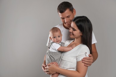 Photo of Happy family. Couple with their cute baby on grey background