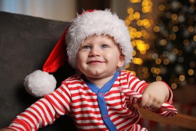 Baby in cute Christmas outfit with candy cane at home