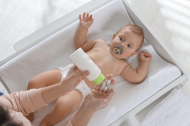 Photo of Mother with dusting powder near her baby at home, closeup