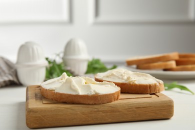 Bread with cream cheese on white wooden table