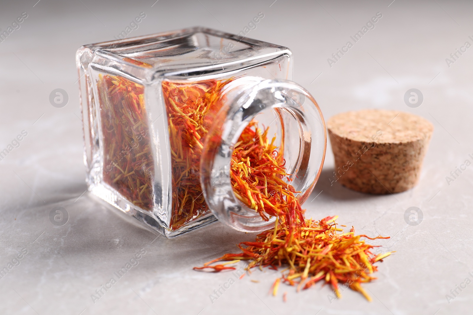 Photo of Aromatic saffron, glass jar and lid on light gray table, closeup