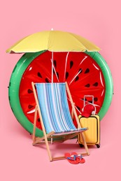 Photo of Deck chair, suitcase and beach accessories on pink background