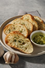 Photo of Tasty baguette with garlic and dill served on grey textured table
