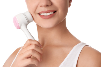 Photo of Young woman washing face with cleansing brush on white background, closeup. Cosmetic product