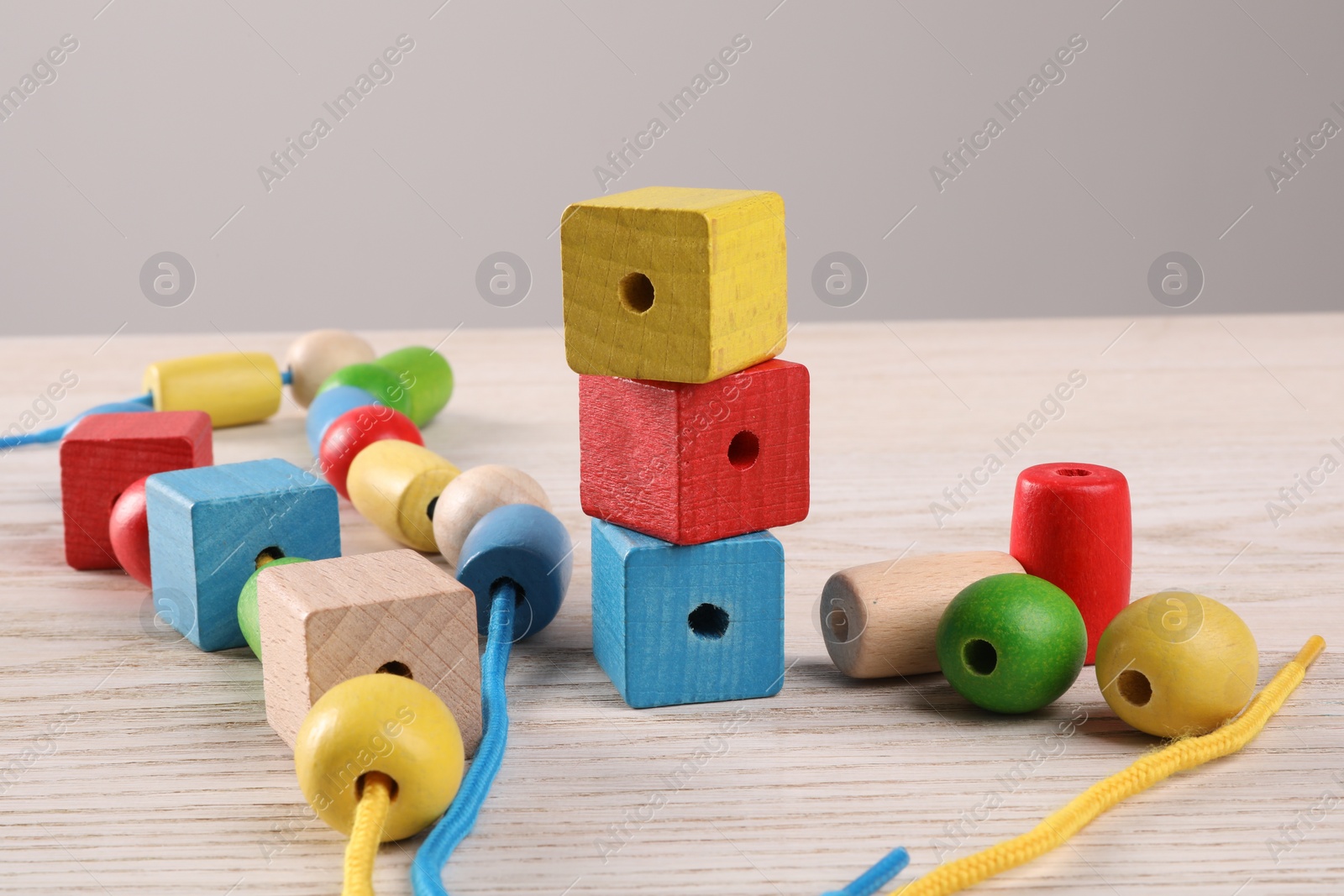 Photo of Wooden pieces and string for threading activity on light table, closeup. Motor skills development