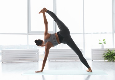 Photo of Young woman practicing extended side plank asana in yoga studio, back view. Utthita Vasisthasana pose
