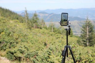 Photo of Taking video with modern phone on tripod in mountains