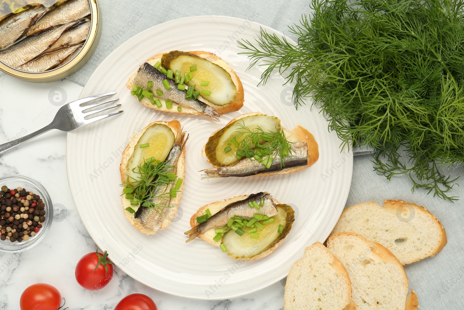 Delicious sandwiches with sprats, pickled cucumber, green onion and dill served on white marble table, flat lay Photo of Delicious sandwiches with sprats, pickled cucumber, green onion and dill served on white marble table, flat lay
