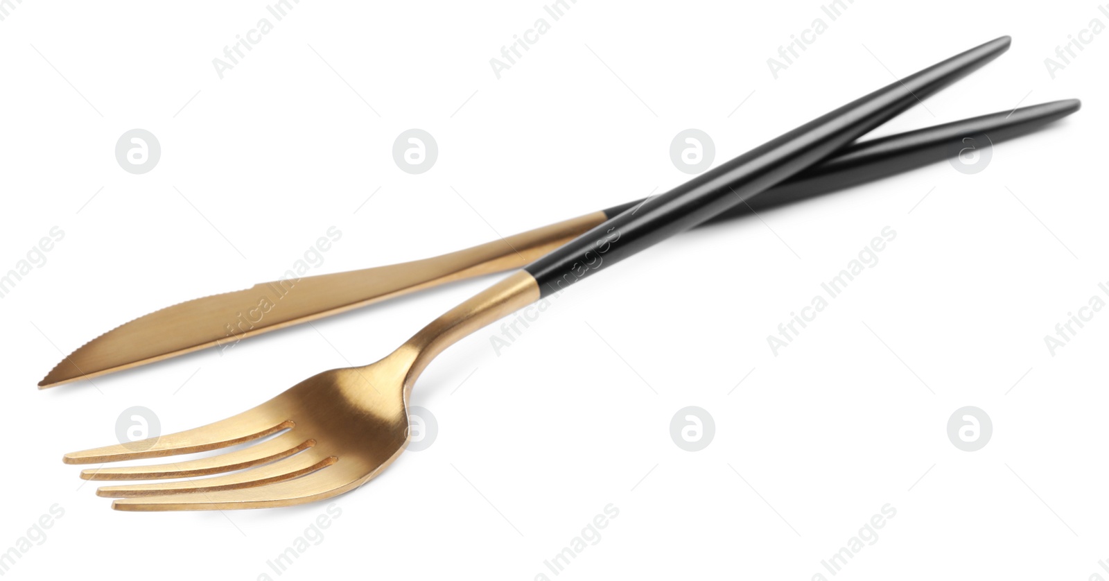 Photo of New golden fork and knife with black handles on white background