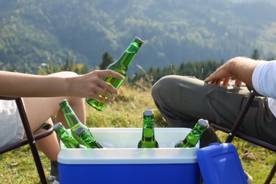 Couple and cool box with bottles of beer in nature, closeup