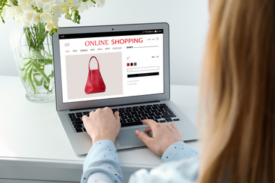 Woman shopping online using laptop at table, closeup