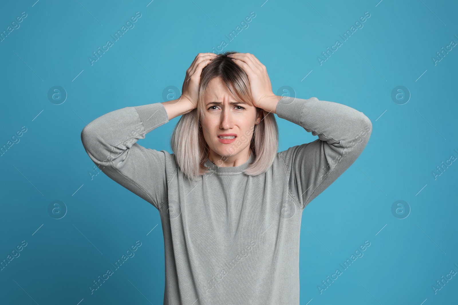 Photo of Woman suffering from headache on light blue background