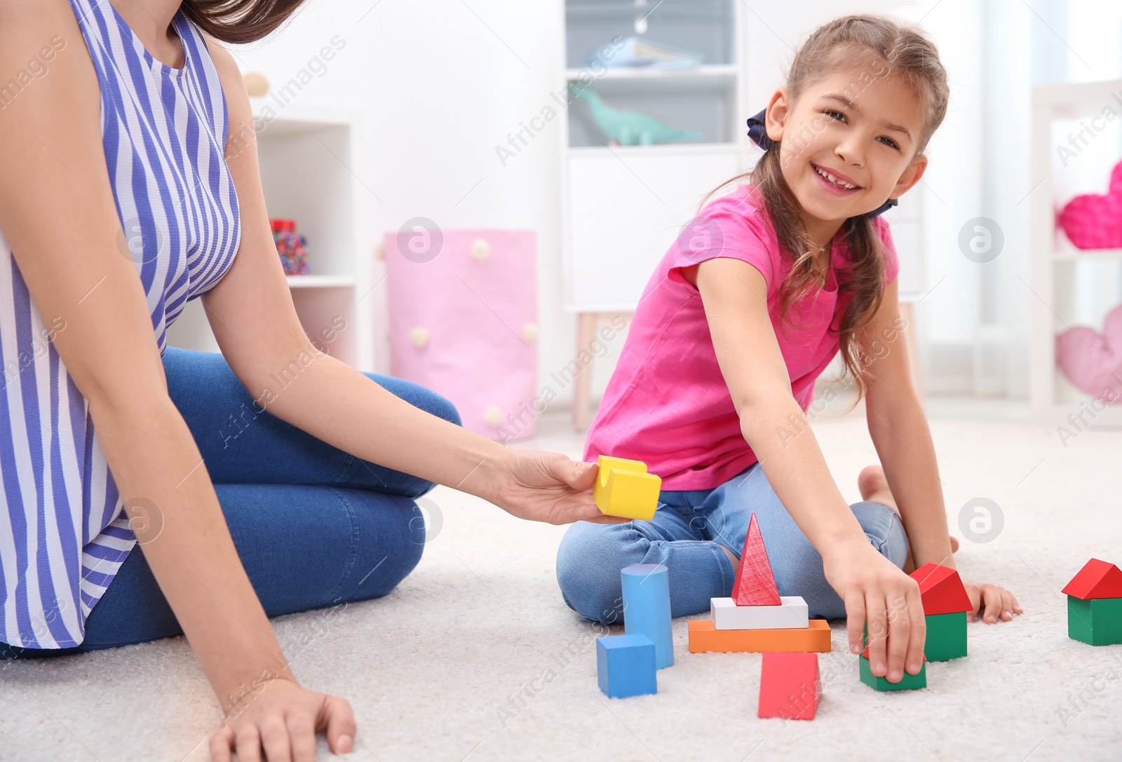 Photo of Woman and her child playing together with colorful blocks at home