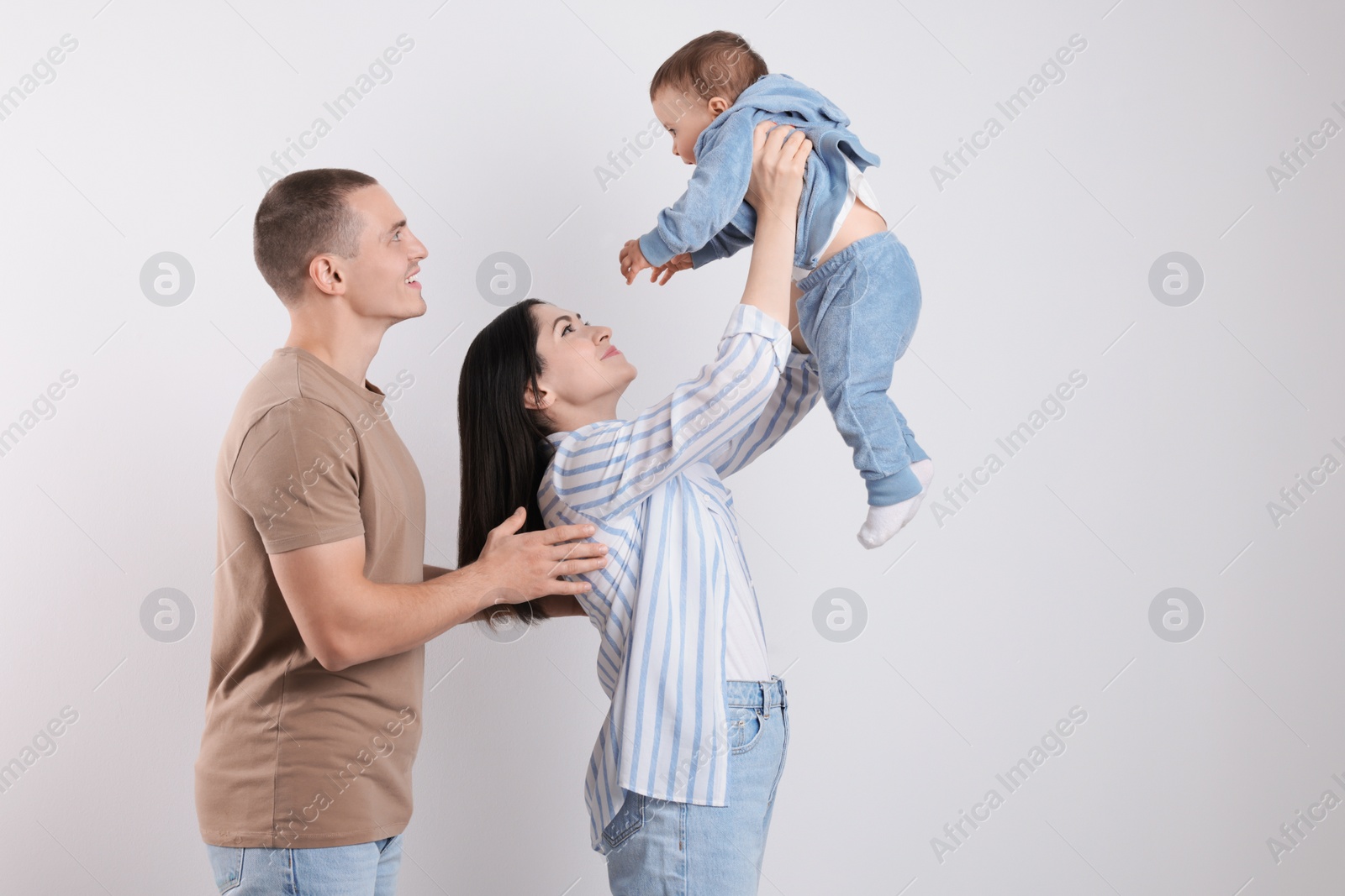 Photo of Happy parents with cute child on light background