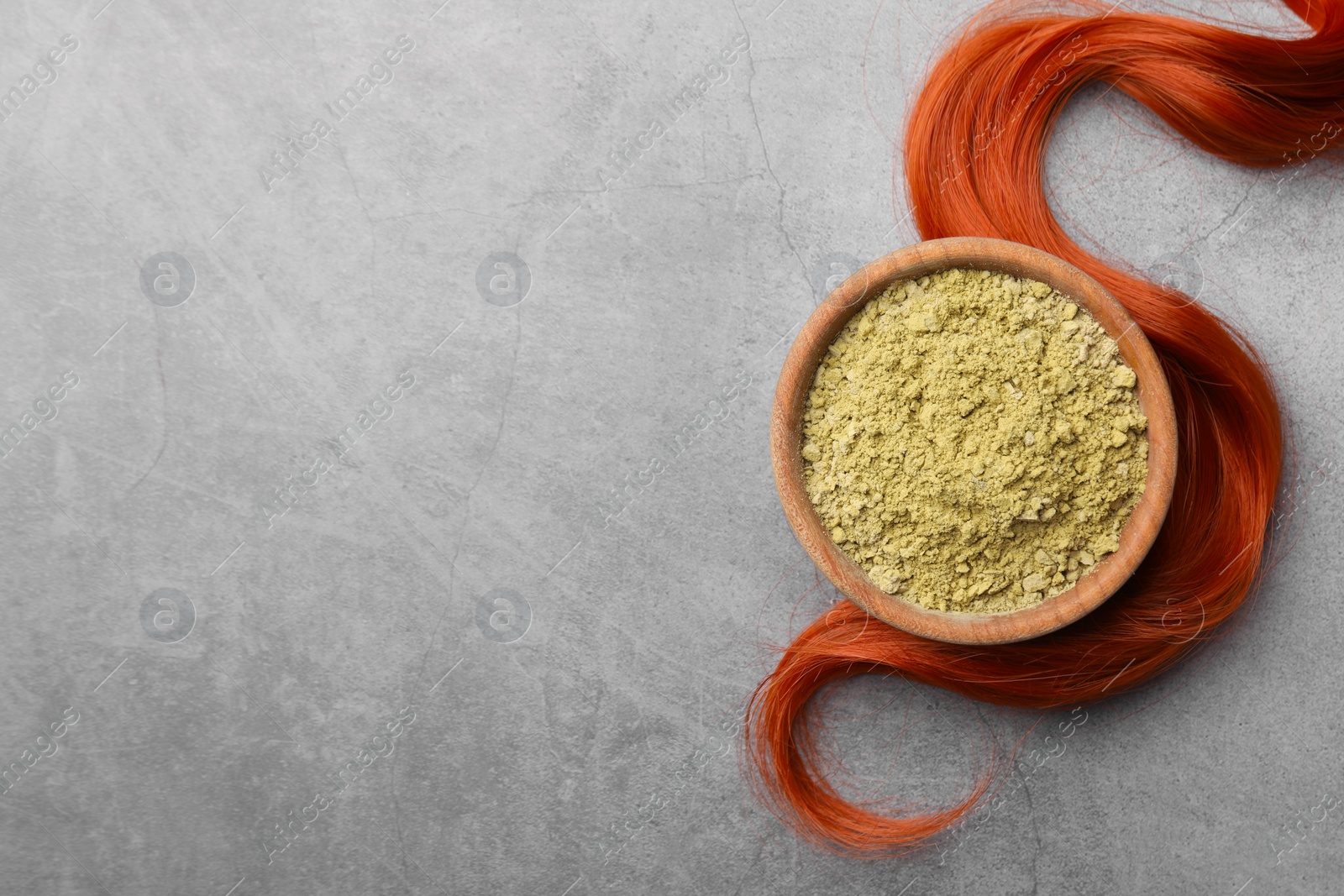 Photo of Henna powder and red strand on grey table, flat lay with space for text. Natural hair coloring