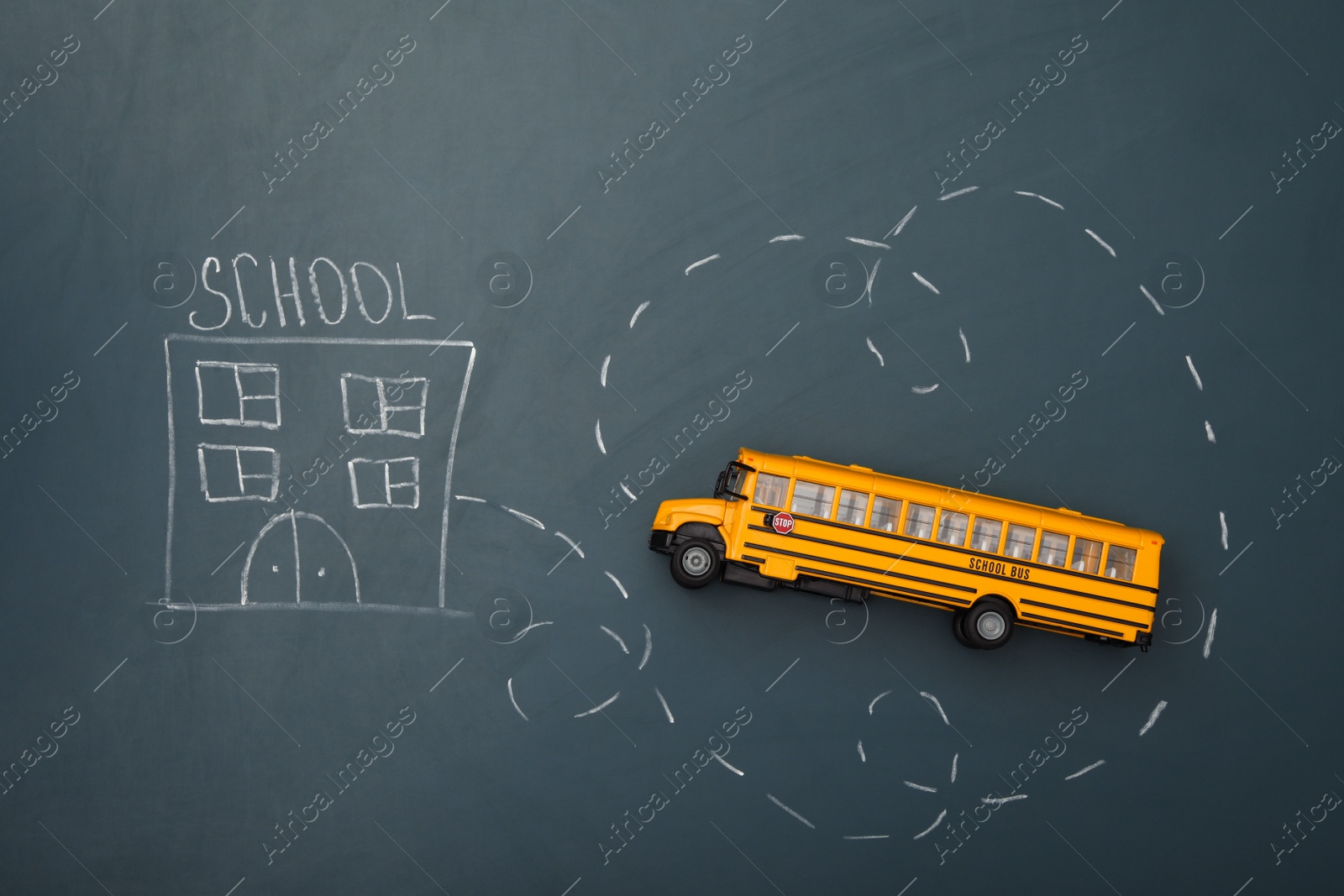 Photo of Yellow bus and drawing of school on chalkboard, top view. Transport for students