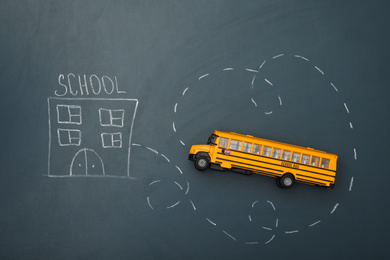 Yellow bus and drawing of school on chalkboard, top view. Transport for students