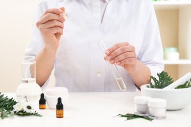 Photo of Female dermatologist creating skin care product at table, closeup