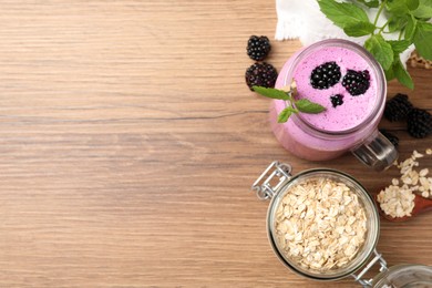 Delicious blackberry smoothie, oatmeal and berries on wooden table, flat lay. Space for text