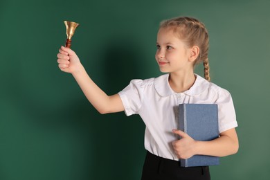 Photo of Pupil with school bell near green chalkboard