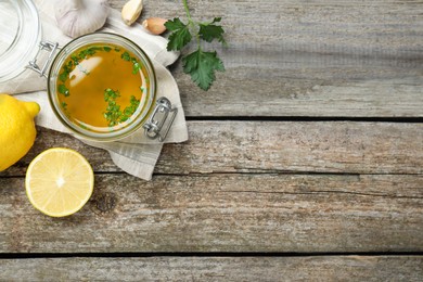 Photo of Jar of lemon sauce and ingredients on wooden table, flat lay with space for text. Delicious salad dressing