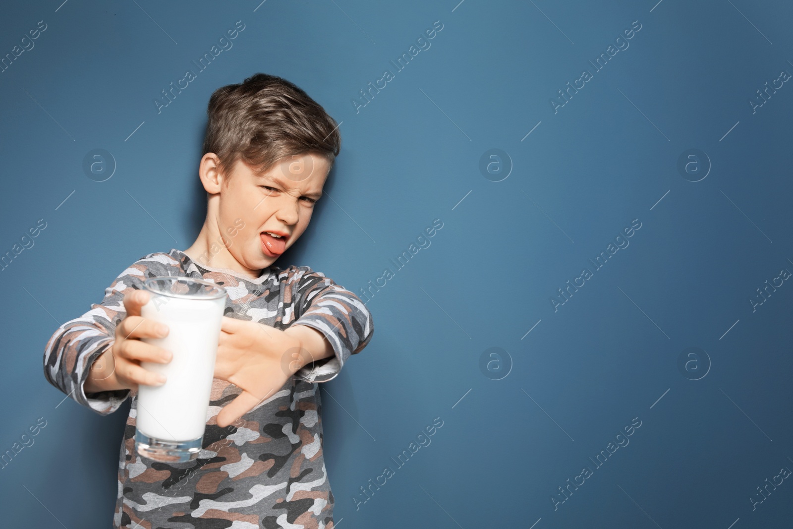 Photo of Little boy with dairy allergy holding glass of milk on color background