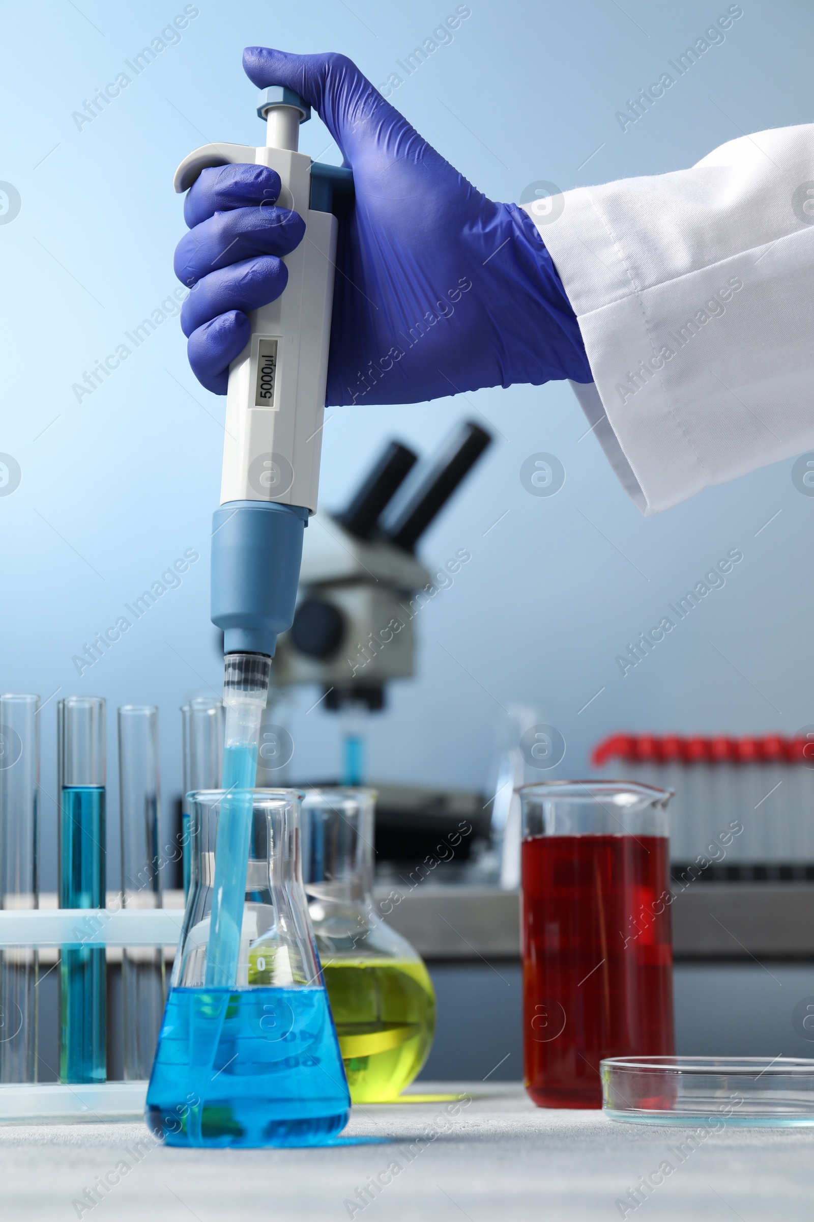 Photo of Laboratory analysis. Scientist dripping sample with micropipette into flask indoors, closeup