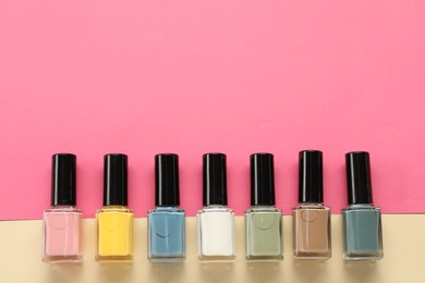 Beautiful nail polishes in bottles on color background, flat lay. Space for text