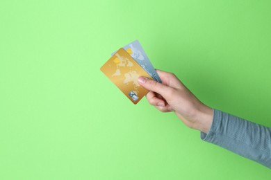 Photo of Woman holding credit cards on light green background, closeup