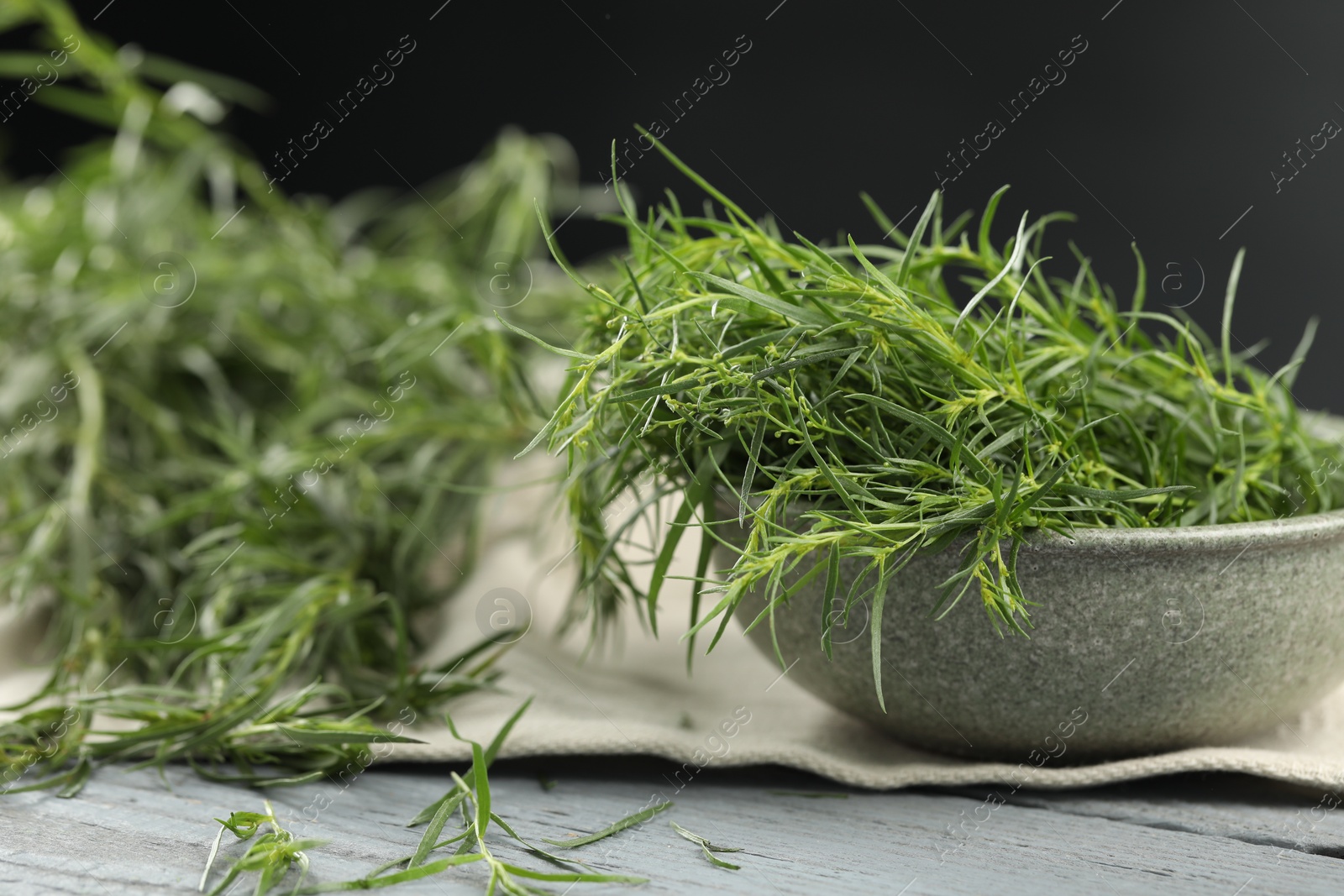 Photo of Fresh tarragon leaves on grey wooden table, closeup