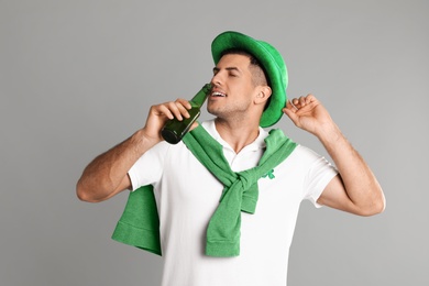 Photo of Man in St Patrick's Day outfit drinking beer on light grey background
