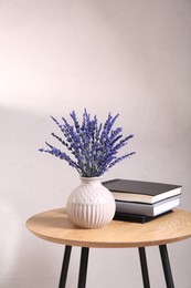 Bouquet of beautiful preserved lavender flowers and notebooks on wooden table near beige wall