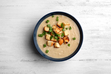 Photo of Bowl of fresh homemade mushroom soup on wooden background, top view