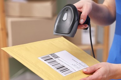 Photo of Parcel packing. Post office worker with scanner reading barcode indoors, closeup