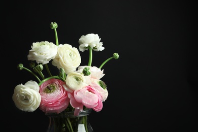 Photo of Glass vase with beautiful ranunculus flowers on black background