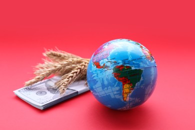 Import and export concept. Globe, ears of wheat and money on red background