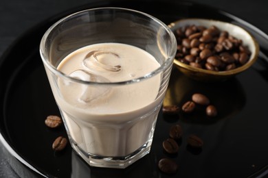 Coffee cream liqueur in glass and beans on table, closeup