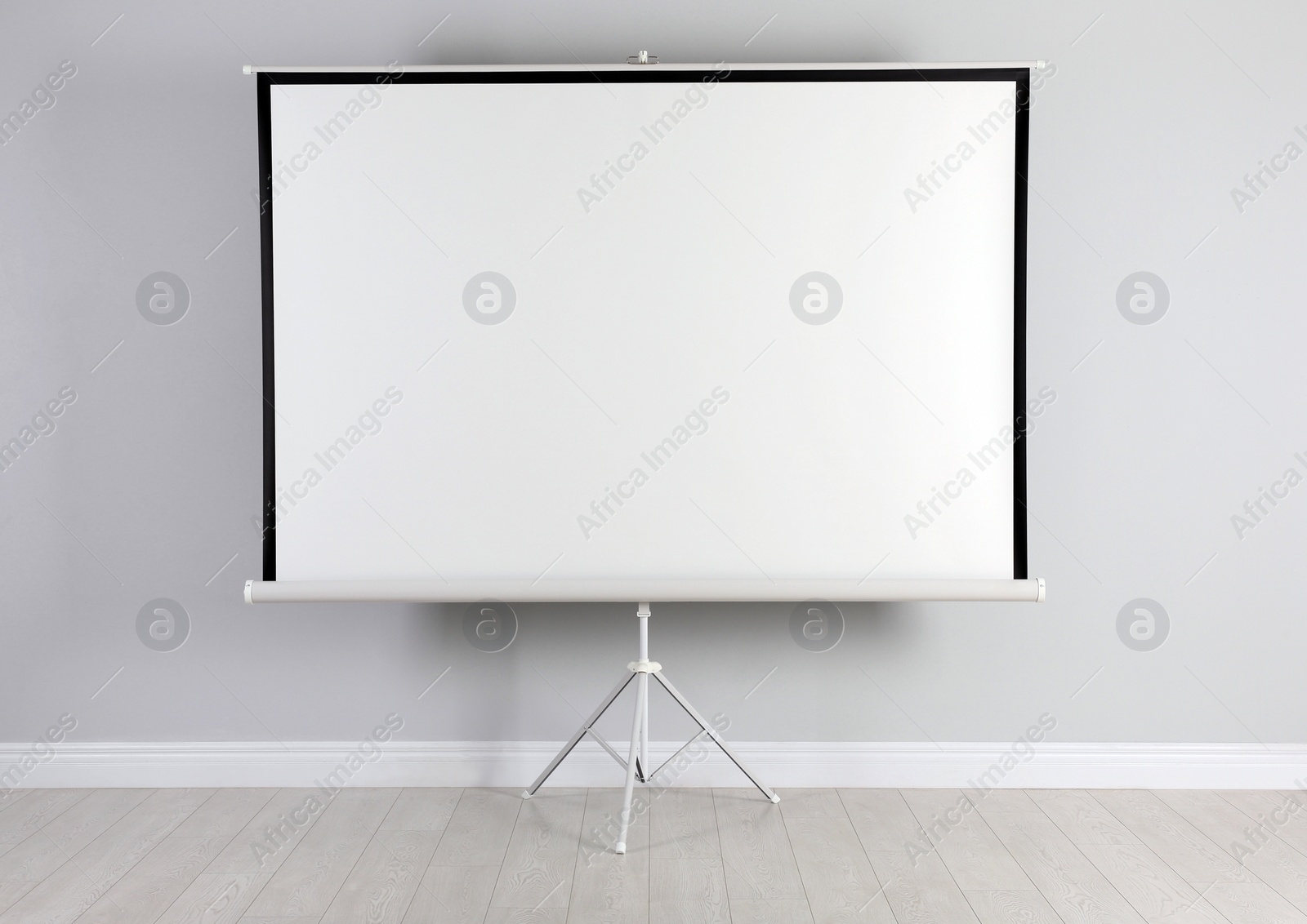 Photo of Blank projection screen near white wall indoors. Space for design