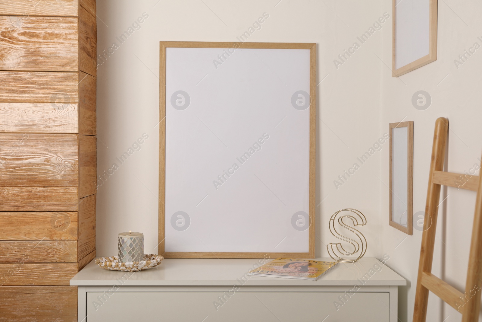 Photo of Blank frame on chest of drawers and decor indoors. Space for design