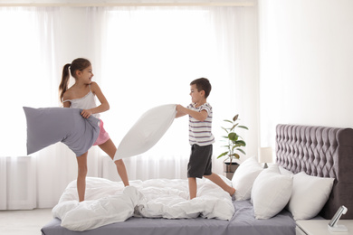 Photo of Happy children having pillow fight in bedroom