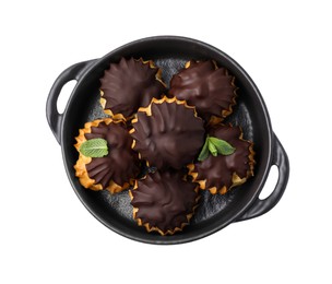 Delicious profiteroles with chocolate spread and mint in frying pan isolated on white, top view