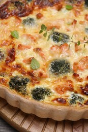 Pieces of delicious homemade quiche with salmon and broccoli on wooden board, closeup