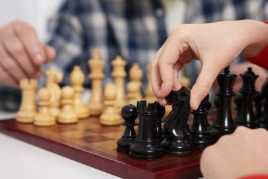 Photo of Grandfather and grandson playing chess at table, closeup