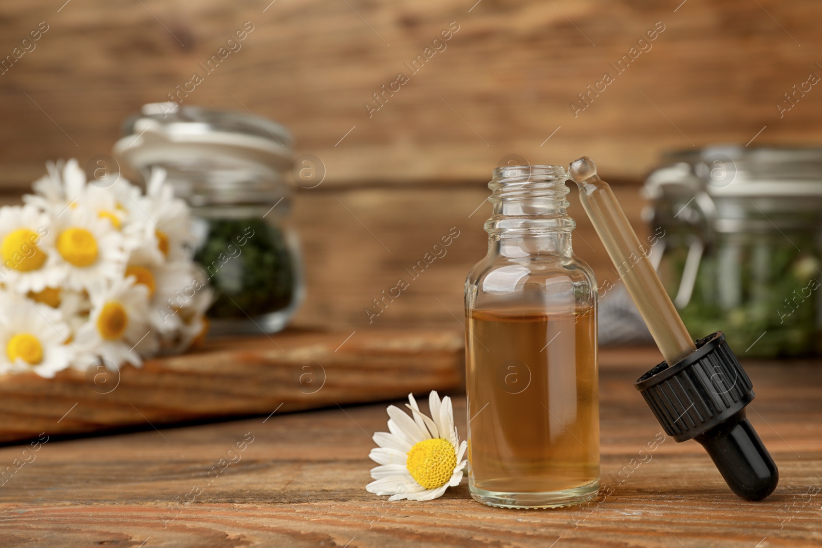 Photo of Composition with bottle of chamomile essential oil on table