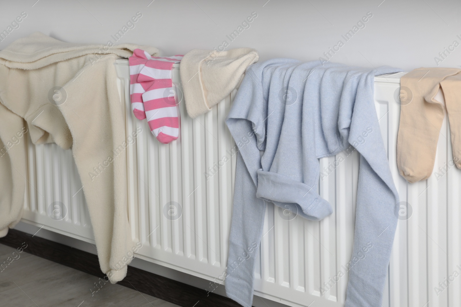 Photo of Clean clothes on white heating radiator indoors